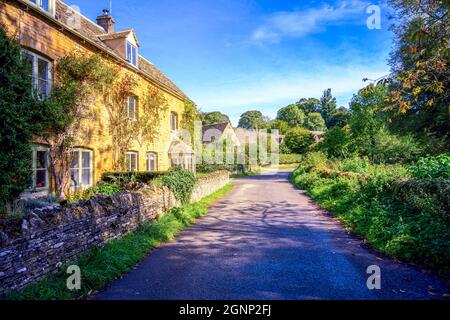 Traditionelle Steinhütten entlang einer Landstraße im hübschen Cotswold Cotswolds-Dorf Upper Slaughter Gloucestershire England, Großbritannien Stockfoto