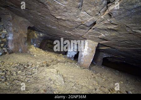 Innenansicht der Eisenerzmine 'Kristian', Westböhmen.eine geneigte Kammer im Bereich der Lagerstätte, mit tragenden Steinsäulen. Stockfoto