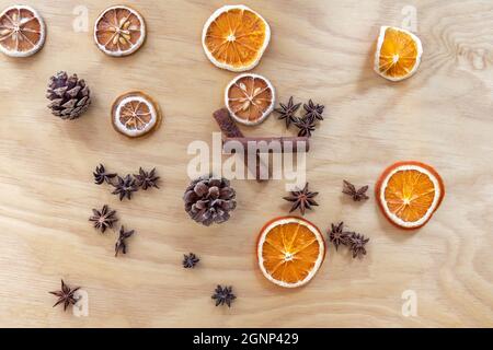 Weihnachtskomposition aus Zapfen, getrockneten Orangen und Zitronen, Zimt und Anissternen. Sperrholz im Hintergrund. Stockfoto