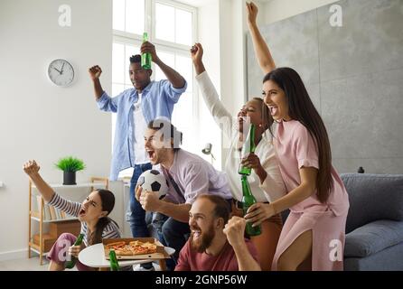 Eine Gruppe junger Fans, die im Fernsehen Fußball schauen, kreischen und ihre Lieblingsmannschaft unterstützen Stockfoto