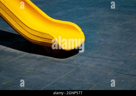 Gelbe Rutsche im Park auf schwarzem Hintergrund. Spielplatzkonstruktion. Minimaler Spielplatzhintergrund. Stockfoto