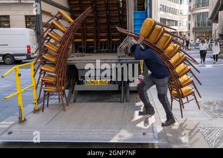 Nach einer Veranstaltung in Lloyds of London in der City of London, dem Finanzdistrikt der Hauptstadt, am 24. September 2021 in London, England, beladen Auftragnehmer des Möbelherstellers „Well dressed Tables“ hohe Stapel von Veranstaltungsstühlen in den Lastwagen des Unternehmens. Stockfoto