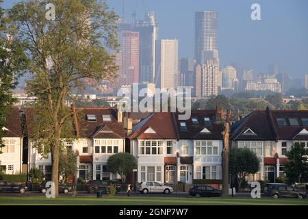 Durch eine Lücke von 100 Jahre alten Eschenbäumen Grenzen edwardianische Wohnhäuser am 16. September 2021 in London, England, an den Ruskin Park im Süden Londons mit Wohnhochhäusern an der entfernten Nine Elms-Siedlung in Battersea. Stockfoto