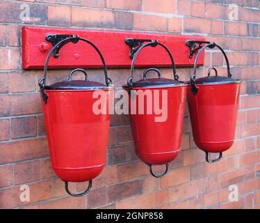 Drei An Der Wand Montierte Rote Feuersandeimer Aus Metall. Stockfoto