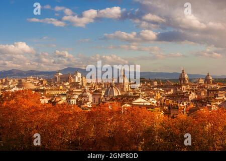 Herbst in Rom. Blick auf die Skyline des historischen Zentrums kurz vor Sonnenuntergang mit alten Denkmälern, barocken Kuppeln und roten Blättern Stockfoto