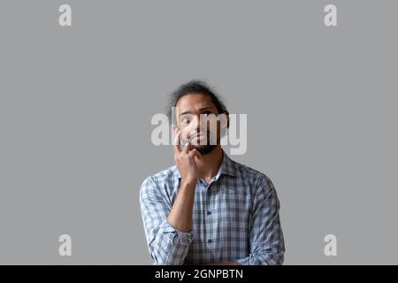 Unglücklicher nachdenklicher afroamerikanischer Mann, der auf grauem Hintergrund aufschaut Stockfoto