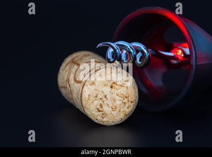 Korkenzieher und Weinstopper auf dunklem Hintergrund mit roten Reflexen. Stockfoto