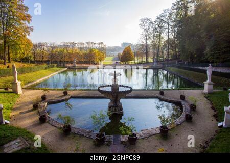 Erstaunlicher Herbst im Saint-Cloud Park in Paris. Teich, Statuen und gelbe und orange Blätter von Bäumen. Menschen, die an einem schönen sonnigen Tag zu Fuß gehen (in der Nähe) Stockfoto