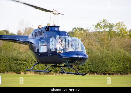 Männliche weibliche Crew Bell Jet Ranger im Schwebeflug mit Beifahrer. G-OCFD. Stockfoto