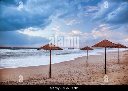 Sonnenschirme mit Sonnenuntergang am Strand von Calabria in Vibo Valentia, Kalabrien, Süditalien Stockfoto