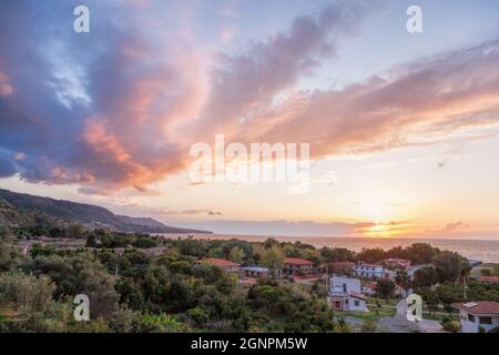 Sonnenuntergang über der Küste Kalabriens mit Dorf neben der Stadt Tropea in Vibo Valentia, Kalabrien, Süditalien Stockfoto