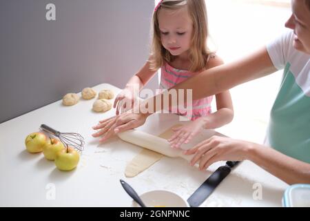 Mutter und Tochter Rollen Mehlteig am Tisch in der Küche aus Stockfoto