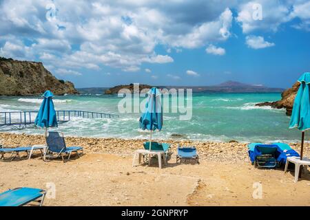 Liegestühle und Sonnenschirme am leeren Strand am stürmischen Tag. Almyrida. Kreta, Griechenland Stockfoto