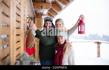 Familie mit kleiner Tochter Dekoration Terrasse des Hauses im Freien im Winter, Weihnachtszeit, Blick auf die Kamera. Stockfoto