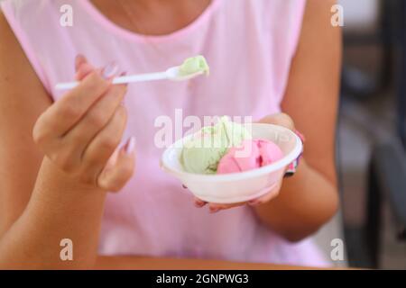 Weibliche Hände halten einen Löffel mit Eis Stockfoto