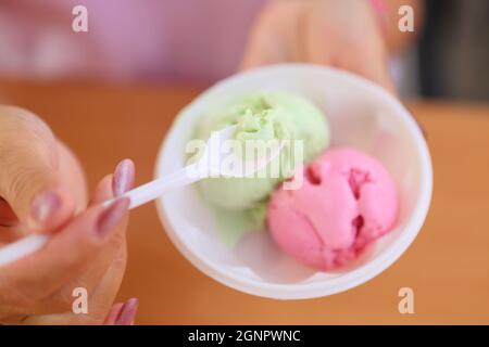 Weibliche Hände halten einen Löffel mit Eis Stockfoto
