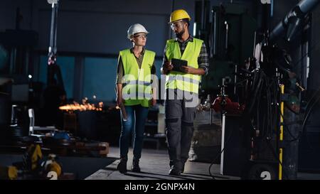 Porträt von Industrieinspektoren, die in Innenräumen in einer Metallwerkstatt eine allgemeine Überprüfung durchführen. Stockfoto