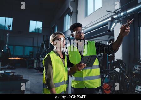 Porträt von Industrieinspektoren, die in Innenräumen in einer Metallwerkstatt eine allgemeine Überprüfung durchführen. Stockfoto