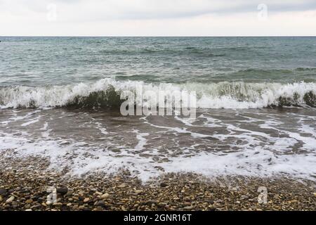 Kleine Sturmwellen an einem Kiesstrand Stockfoto