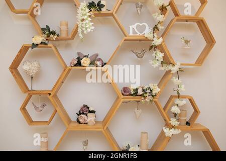 Die Inneneinrichtung ist sehr dekorativ. Wand mit hölzernen Wabenregalen. Trendiges Design. Hochzeitsdekorationen Stockfoto