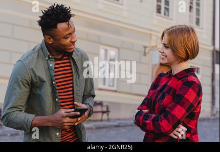 Junger Mann, der draußen auf der Straße mit Freundinnen spricht. Stockfoto