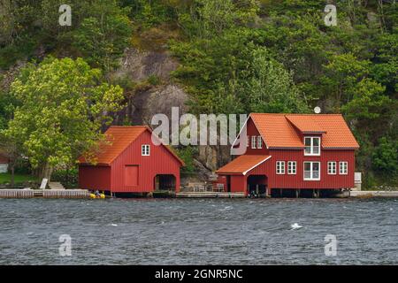 ÅNA-SIRA, NORWEGEN - SEPTEMBER 08. Rotes Haus zusammen mit einem Bootshaus in der Nähe des Meeres. Stockfoto