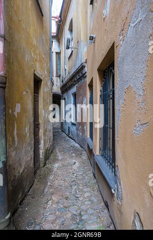 VILNIUS, LITAUEN – 2020. MÄRZ 06. Eine enge Straße mit zwei gelagerten Häusern und einer gepflasterten Straße in der Altstadt von Vilnius. Stockfoto