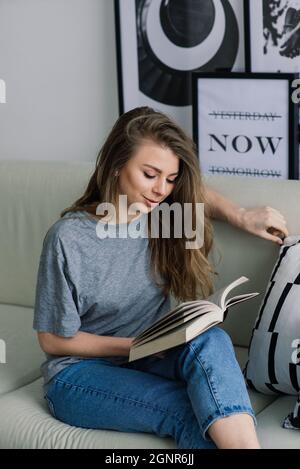 Junge Frau, die zu Hause in der Lounge auf dem Boden sitzt und auf dem Sofa mit einem Laptop arbeitet Stockfoto
