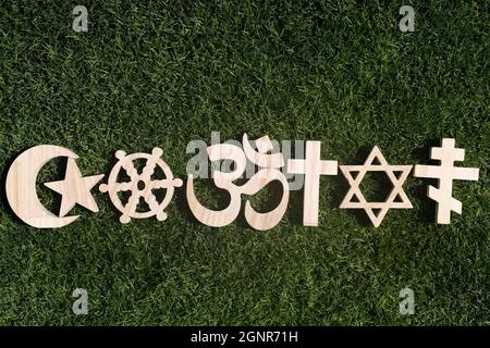 Religiöse Symbole auf Gras. Christentum, Islam, Judentum, Orthodoxie-Buddhismus und Hinduismus. Interreligiöses oder interreligiöses Konzept. Stockfoto