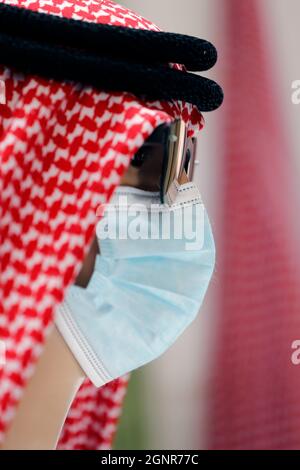 kufiya - traditioneller arabischer Kopfschmuck für Männer an einer Schaufensterpuppe in einem orientalischen Bekleidungsgeschäft. Covid-19-Pandemie. Chirurgische Maske. Dubai. Vereintes Arabisches Emirat Stockfoto