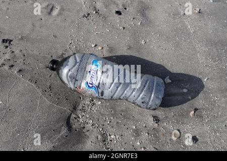 Eine leere zertrümmerte Plastikwasserflasche an einem Sandstrand. Vereinigte Arabische Emirate. Stockfoto