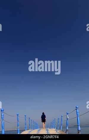 Frau, die auf einem Plastikponton-Spaziergang im Meer schwimmt. Al Hamra Beach am Arabischen Golf bei Ras Al Khaimah. Vereinigte Arabische Emirate. Stockfoto