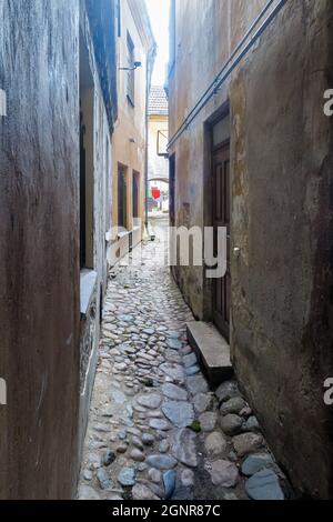 VILNIUS, LITAUEN – 2020. MÄRZ 06. Eine enge Straße mit zwei gelagerten Häusern und einer gepflasterten Straße in der Altstadt von Vilnius. Stockfoto