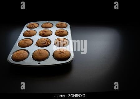 Frisch gebackene Cupcakes auf einem Backblech auf dunklem Hintergrund Stockfoto