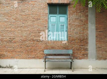 Ziegelgebäude mit blauem Holzfenster und Bank Stockfoto