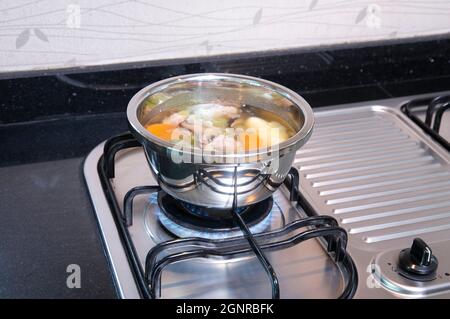 Edelstahlpfanne mit Suppe auf dem Gasherd in der Küche Stockfoto