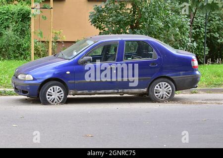 Das beschädigte Auto steht auf Platten Reifen auf dem Parkplatz. Ausschuss. Stockfoto