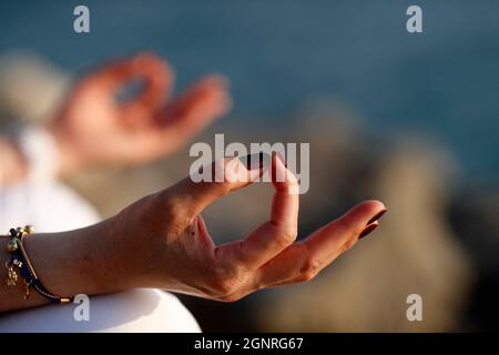 Nahaufnahme der Hände einer jungen sportlichen Frau, die in Lotusposition Meditation praktiziert. Yoga. Stockfoto