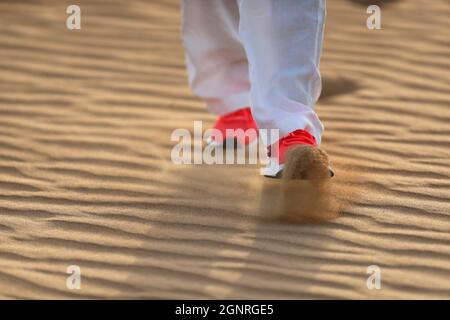 Frau, die in Wüstensanddünen wandert. Nahaufnahme der Schuhe. Dubai. Vereinigte Arabische Emirate. Stockfoto