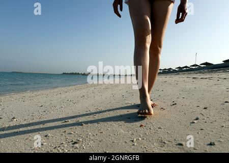 Al Hamra Beach am Arabischen Golf bei Ras Al Khaimah. Frau, die am Strand läuft. Frau, die barfuß am Strand läuft. Vereinigte Arabische Emirate. Stockfoto