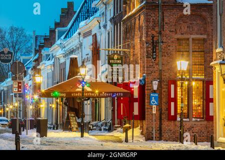 Doesburg, Niederlande - 10. Februar 2021: Schneebedeckte historische Straße mit Restaurants und weihnachtsschmuck im Winter in Doesburg, T Stockfoto