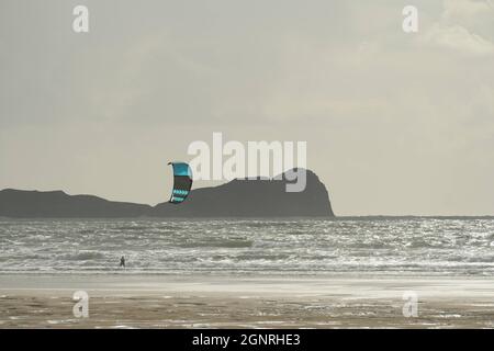 Gower, Swansea, Großbritannien. September 2021. UK Wetter: Ein windiger Herbsttag mit Sonnenschein und Schauern am Llangennith Beach auf der Gower Halbinsel. Ein Kite-Surfer nutzt die steife Onshore-Brise. Das Vorgebirge Worms Head ist im Hintergrund bei Rhossili Bay abgebildet. Kredit: Gareth Llewelyn/Alamy Live Nachrichten Stockfoto