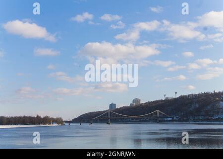 Eiskalt Fluss Dnepr in Kiew. Blick auf die Pechersker Hügel im Winter. Die Hänge der Hügel der Stadt sind mit Schnee bedeckt. Wolken über dem Fluss Stockfoto