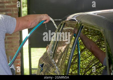 Fahrzeugdetails. Manueller Waschmotor mit Wasser. Waschmotor mit Wasserdüse. Auto waschen Mann Arbeiter Reinigung Fahrzeug.Mann Spritzdruck war Stockfoto