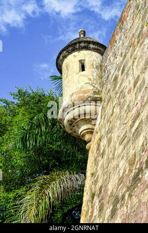 Ein Wachturm und eine Steinmauer der historischen Stadtmauer ragt über einem öffentlichen Gehweg des Old San Juan. Speicherplatz kopieren Stockfoto