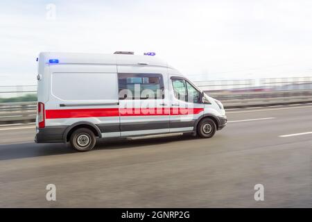 Ambulanzwagen, der bei einem Notruf die Autobahn herunterrast, Seitenansicht Stockfoto