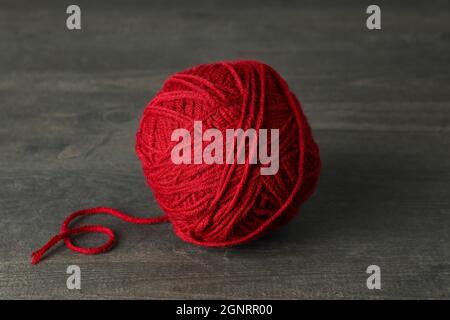 Rote Garnkugel auf grauem Holztisch Stockfoto