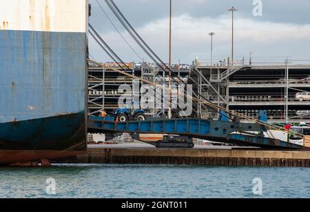 Southampton Docks, England, Großbritannien. 2021. Der Traktor wird über eine Rampe am Dock auf das handelsschiff roro verladen. Stockfoto