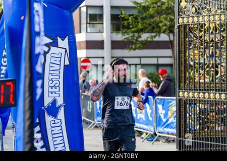 Warrington Running Festival 2021 - der Läufer zieht die Kopfhörer aus, als er die Linie überquert Stockfoto