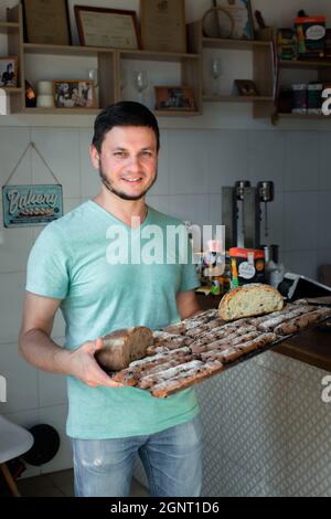 Der junge Bäcker zeigt sein handwerkliches Sauerteig-Brot. Erfolgskonzept, endgültig. Stockfoto